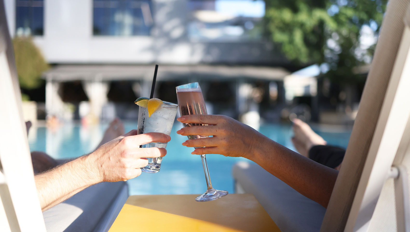 Couple cocktail cheers in lounge chairs at sawyer pool