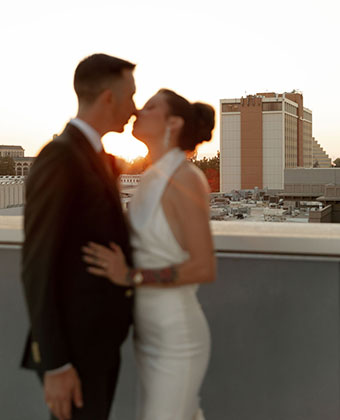 couple kissing in foreground, hotel in the background