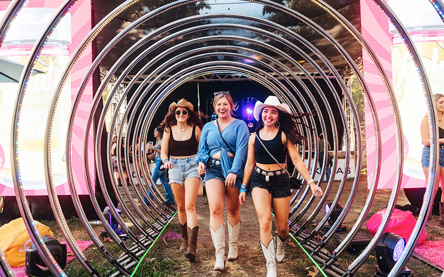 girls in westernwear walking through a tunnel of lights