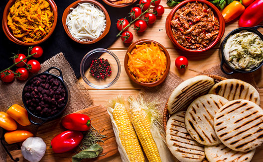 View from above of a wooden rustic table with several ingredients for cooking and filling arepas, typical Latin American food.